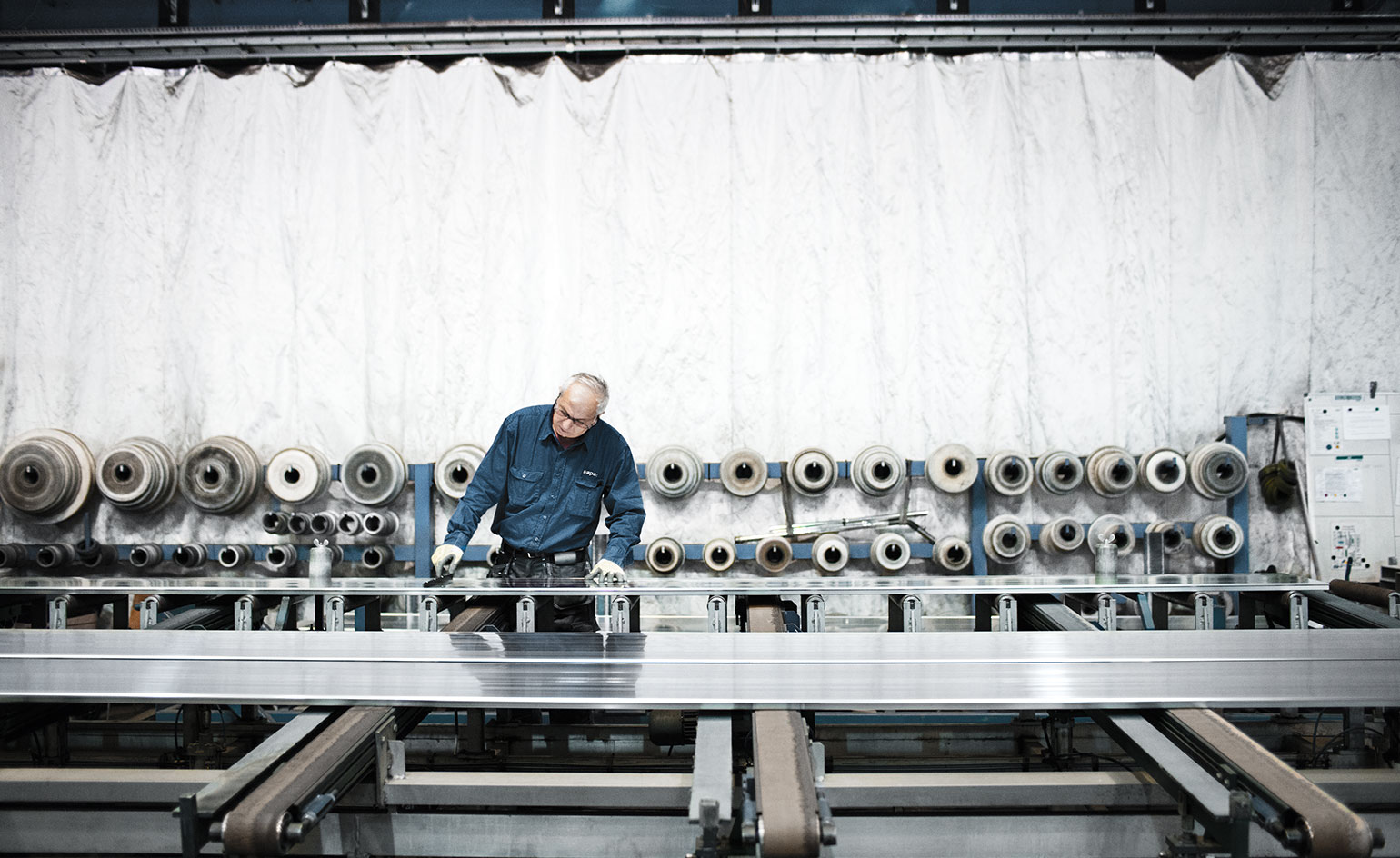 A technician inspects profiles as they run down the extrusion line