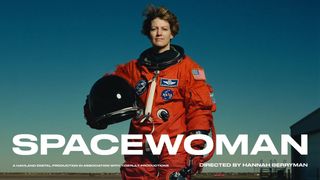 eileen collins standing in front of a blue sky in an astronaut flight suit, holding a helmet