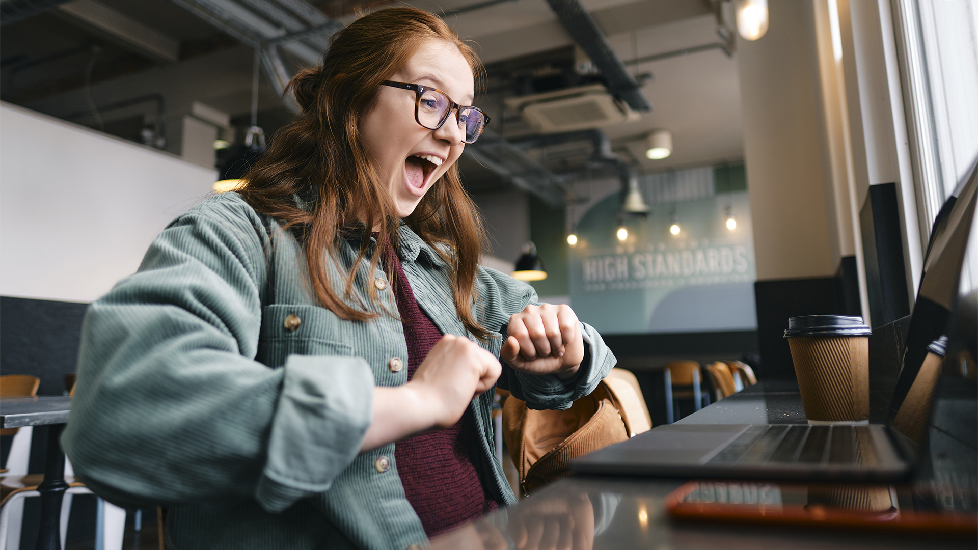 Successful young freelancer screaming at cafe