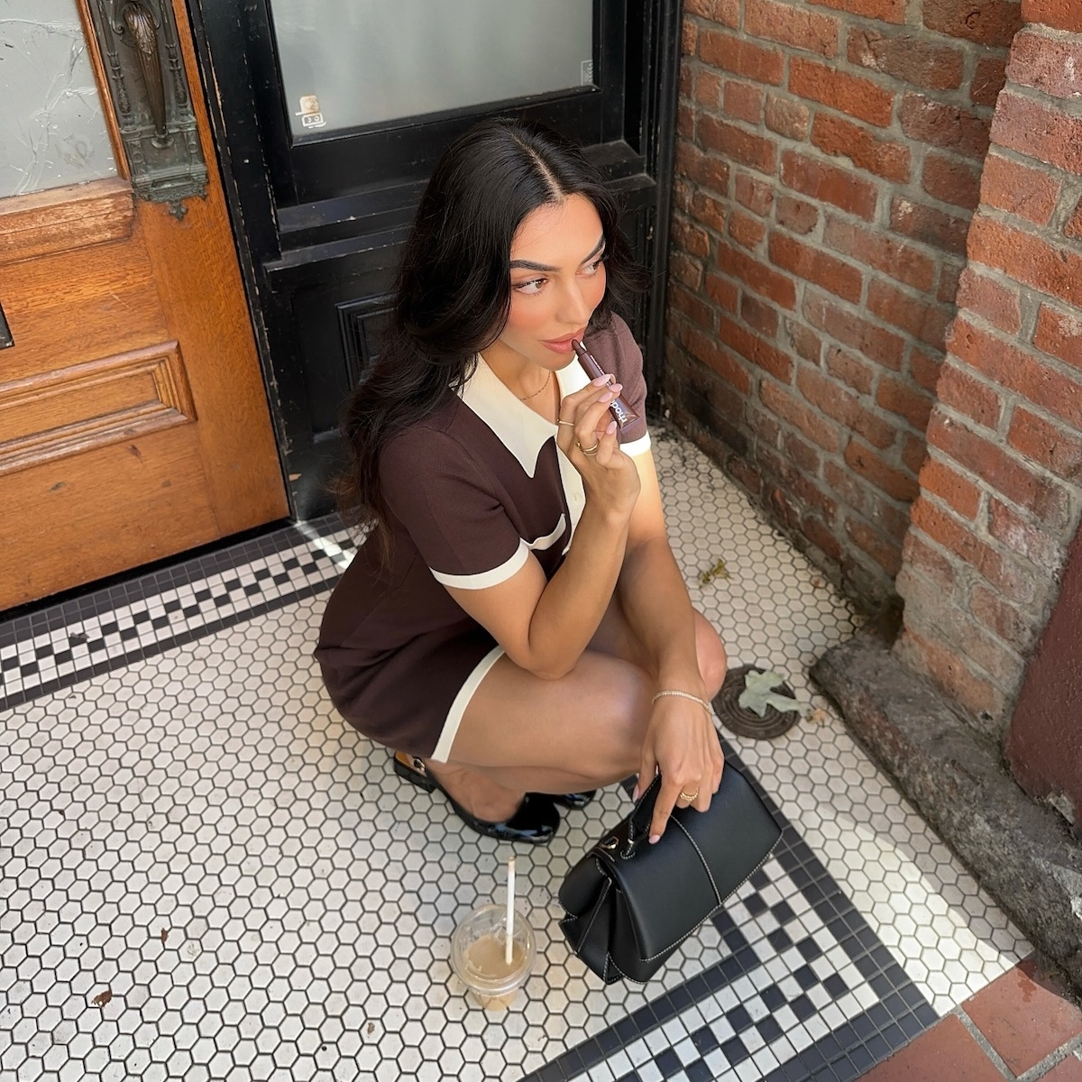 Woman applying lip gloss on a city stoop