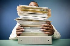 Man balancing a stack of paperwork