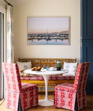 breakfast nook with white round table and red chairs with patterned upholstery