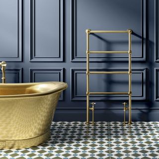 navy blue bathroom wall panelling with brass freestanding bath and brass towel warmer