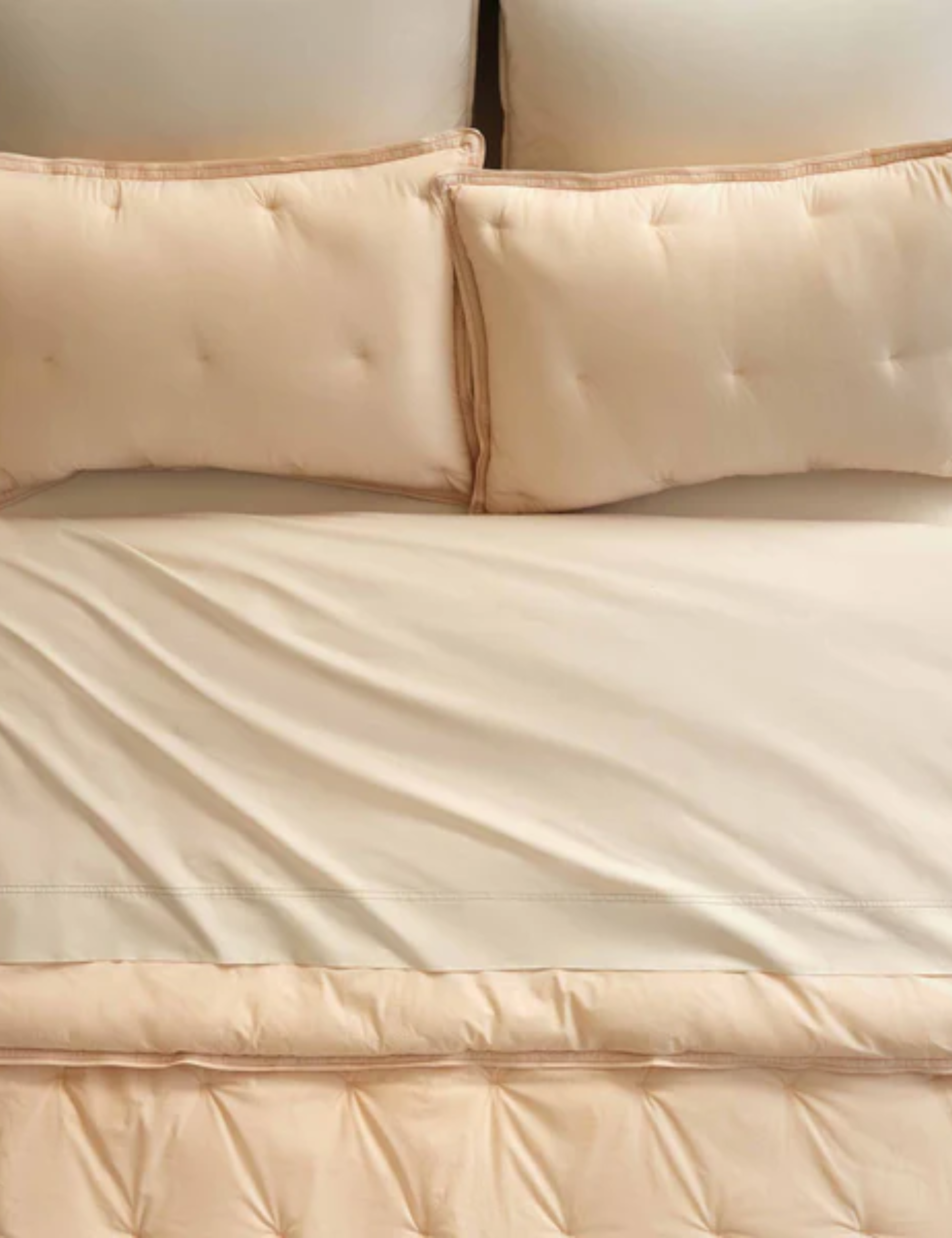 Brooklinen Percale Comforter in Apricot Chambray styled with beige sheets from a bird's eye view