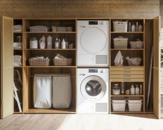 Laundry room with built in closets housing washer dryer stacked vertically and neatly organized shelves with baskets of cleaning products and drawers as well as hampers