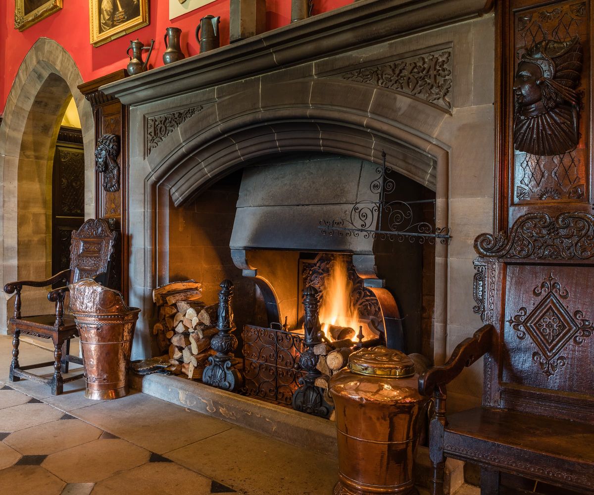 A large stone fireplace with logs stacked up next to it