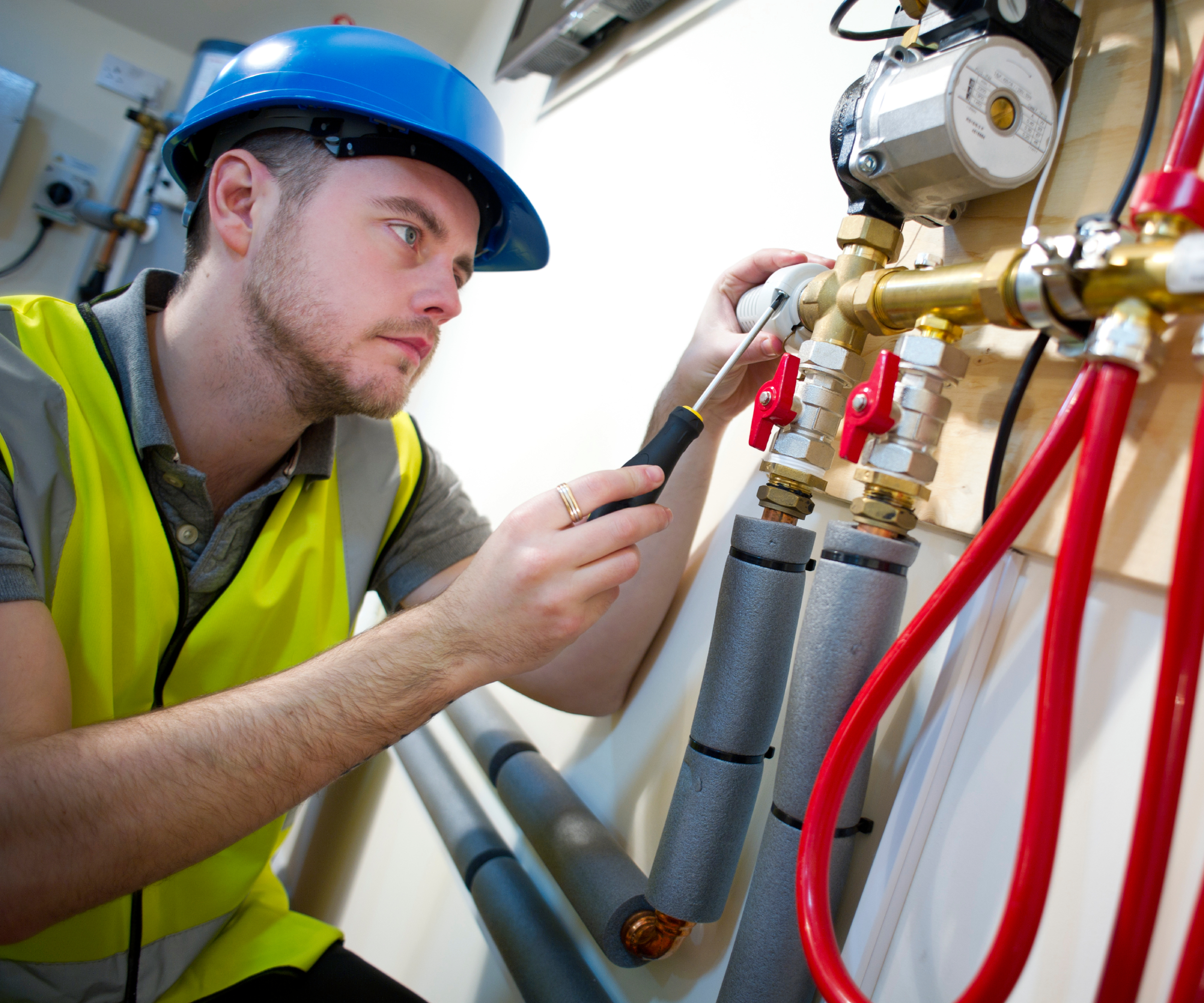 plumber wearing hi-vis and hard hat installing underfloor heating