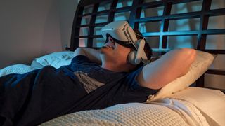 Lying on a bed wearing a Meta Quest 2 with a Kiwi Design audio/battery headstrap