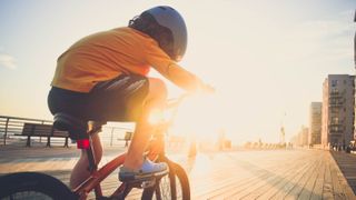 A child riding a bike into a sunset next to the ocean 