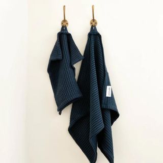 Bamboo Towel Set hanging from hooks in the bathroom wall.