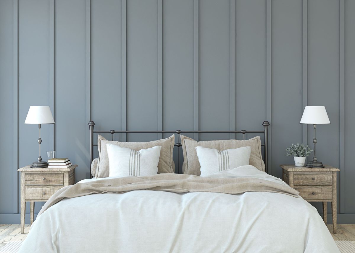 A large bed with white sheets and a grey panelled wall