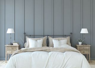 A large bed with white sheets and a grey panelled wall