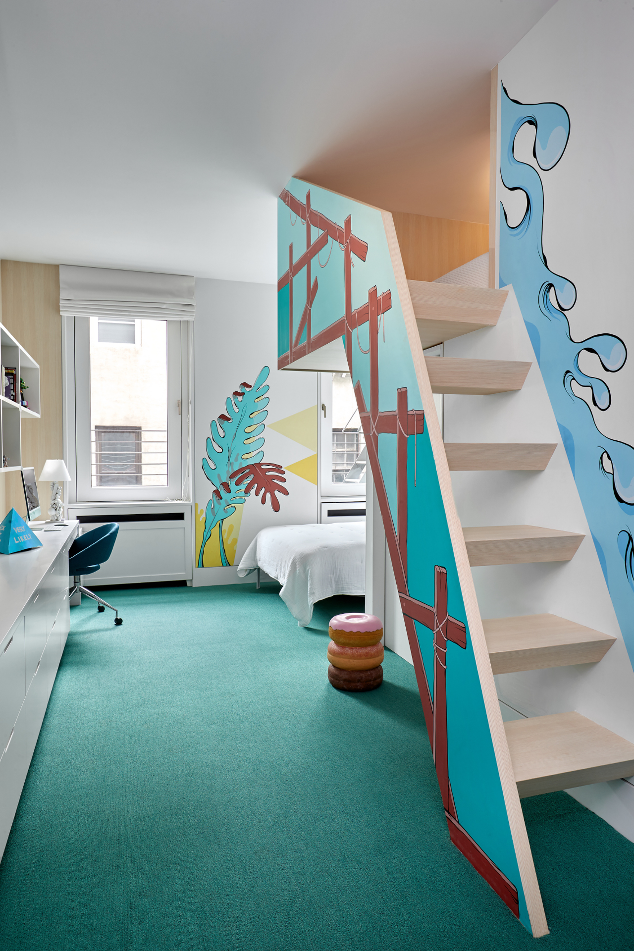 in this angle of the kids' room the carpet looks almost green and you can see the bed in the corner in the distance with the desk seating along the left but the main view is of the decorated stairs leading up to another bedroom space above