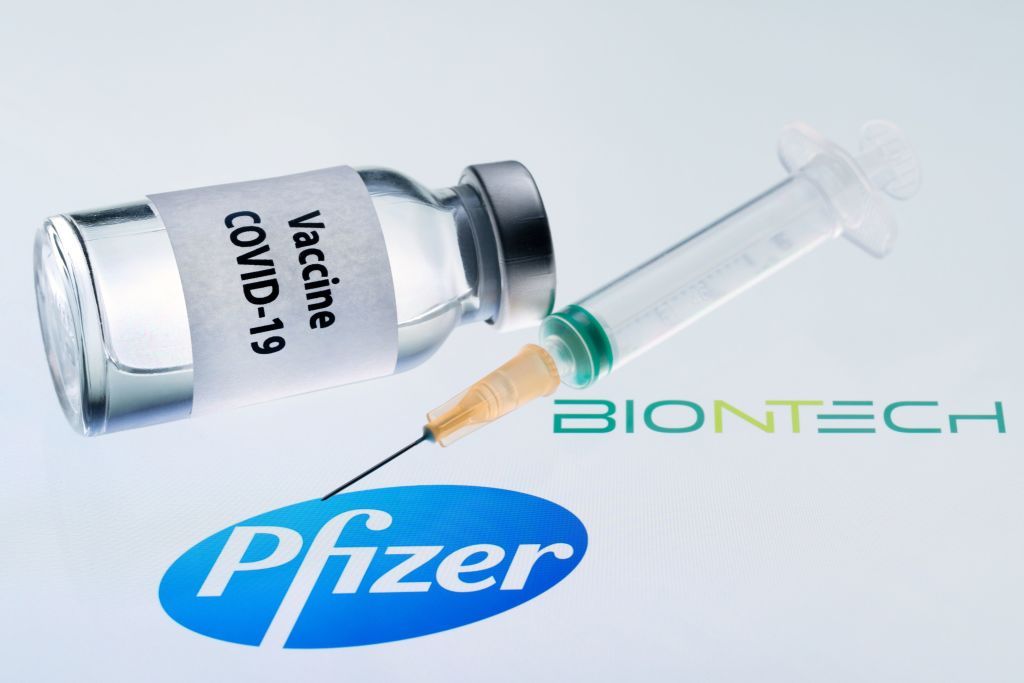 This illustration picture taken on November 23, 2020 shows a bottle reading &amp;quot;Vaccine Covid-19&amp;quot; and a syringe next to the Pfizer and Biontech logo