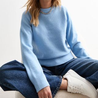 Flat lay image of a woman wearing blue knitted jumper