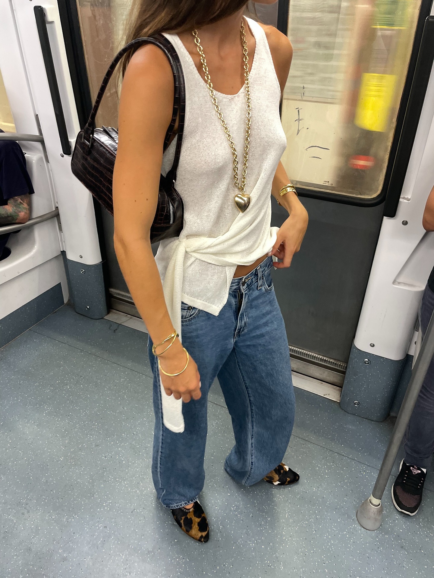 Influencer @lunaisabellaa wears a white tank top with blue low-rise jeans and animal print pony hair shoes.