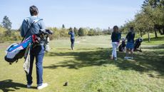 A mixed fourball on the tee, with a female golfer hitting a tee shot