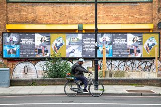 work for Dancing before the moon on a posters on a London street with a person on a bike riding past