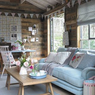room with sky blue sofa wooden wall and bunting