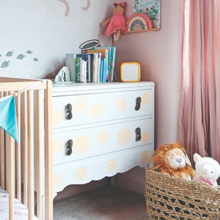 A kids' room with a storage chest of drawers painted with shells and a basket of soft toys next to it