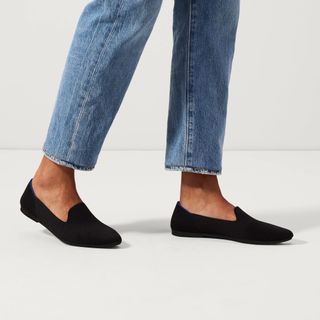 A woman wearing blue jeans and a pair of black Rothy's Almond Loafer flats
