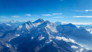 aerial view of mount everest and its surrounding peaks on a clear day with blue sky