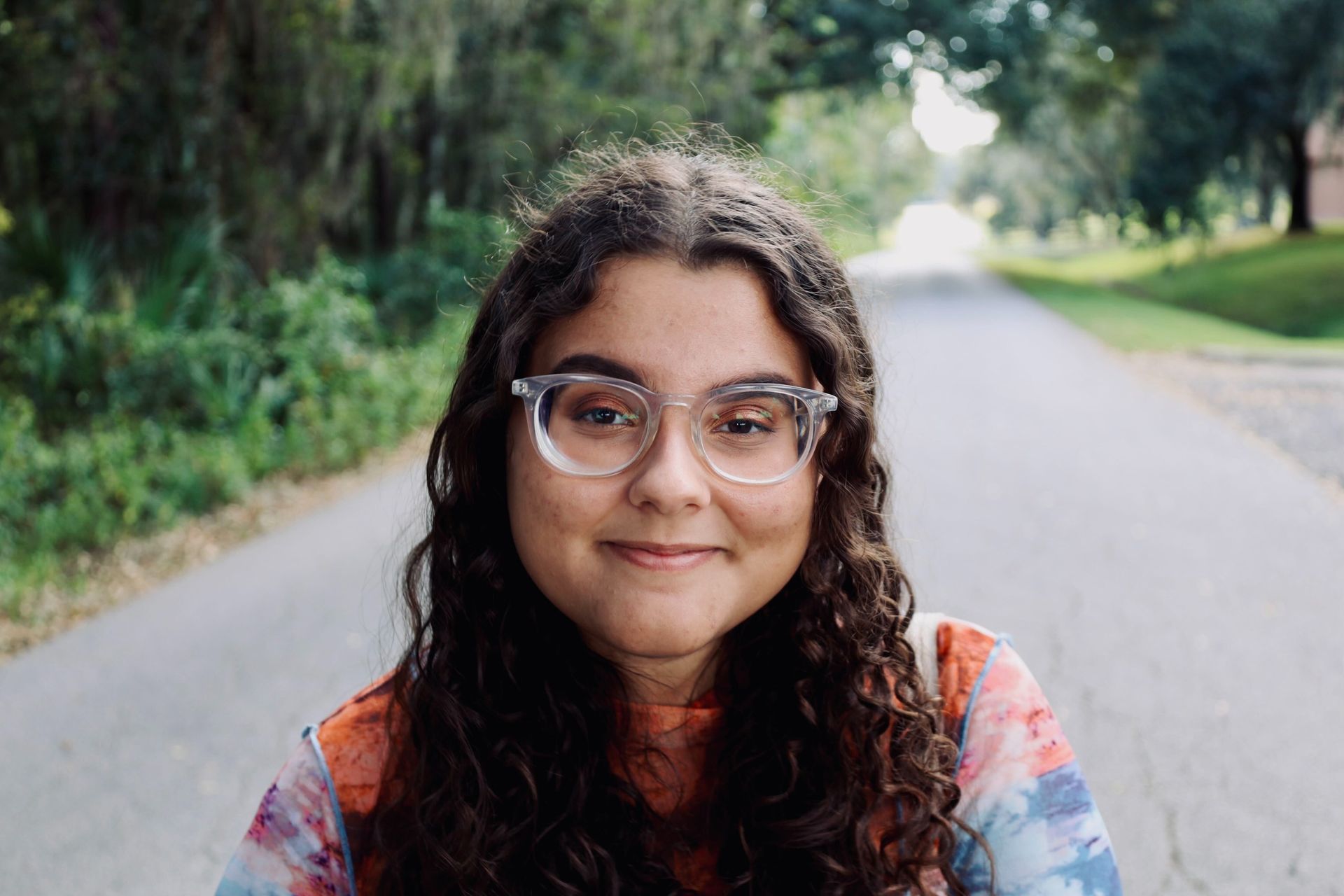 Rachel Newman smiling outdoors on a tree-lined path.