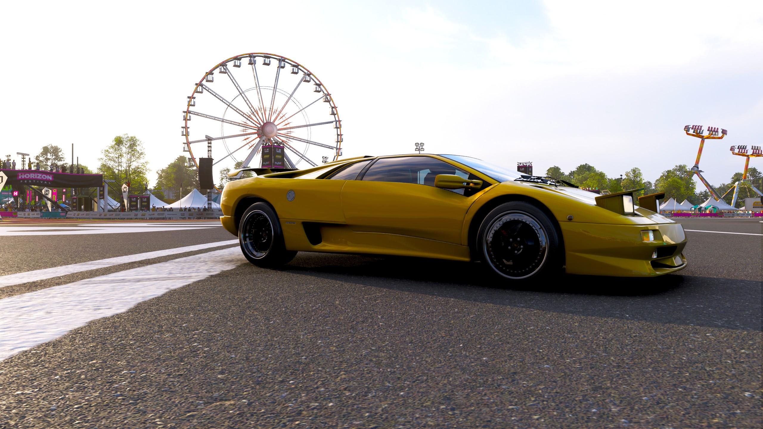 An image of the Lamborghini Diablo SV at the Horizon Festival Outpost in Forza Horizon 6. A big wheel fairground ride is in the background.