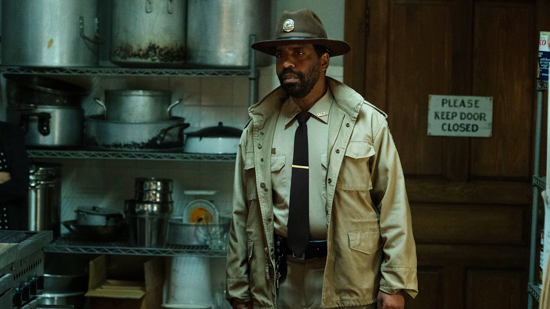 Police chief Bechir standing in a restaurant's kitchen in Widow's Bay on Apple TV