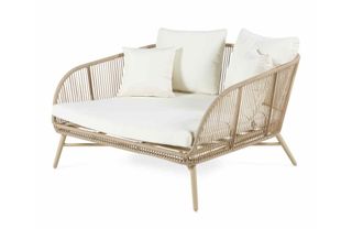 A rattan-effect daybed with cream cushions