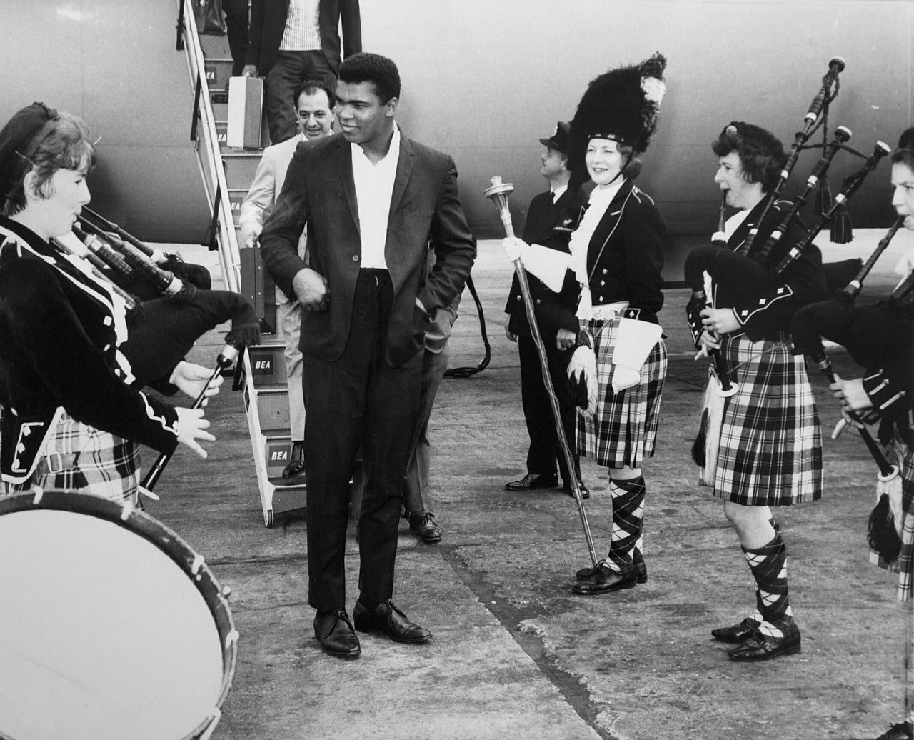 Muhammad Ali is greeted by pipers as he steps off plane in Scotland