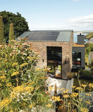 modern brick house with solar planels and large glazing panels nestled amongst trees