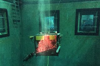 MBARI's MiniROV with its DeepPIV system undergoing trials in a test tank. Bubbles in the water in front of the ROV are illuminated by a sheet of light from the laser at lower left.
