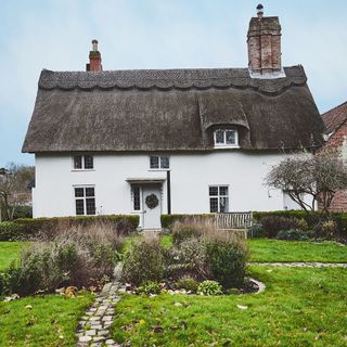white cottage with grey roof and green lawn