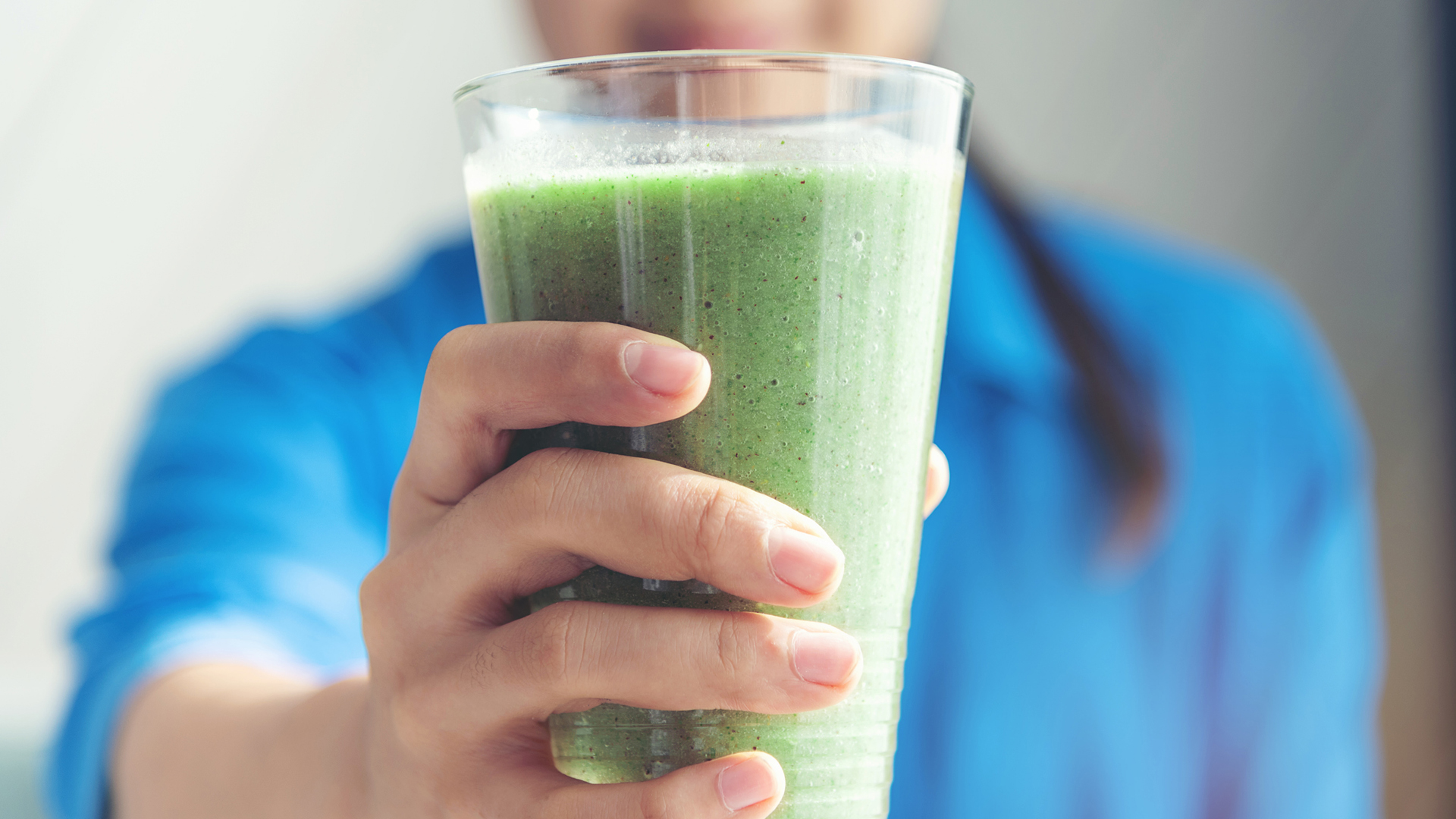 woman drinking a green smoothie