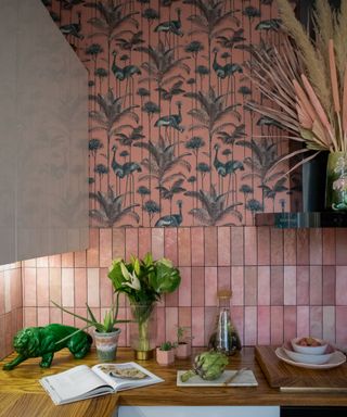 pink rectangular tiles laid vertically with pink and green peacock and plant wallpaper above