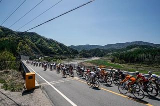 The Tour de Korea peloton races under blue skies and sunshine.