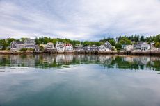 The town of Stonington, Maine, with houses on the water and forests in the background.
