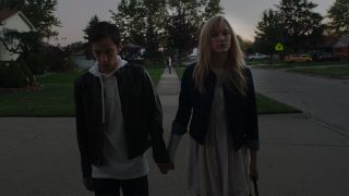 Maika Monroe and Keir Gilchrist holding hands in It Follows