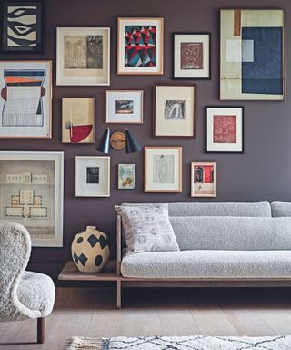 A low couch in a blue living room with a large gallery wall behind