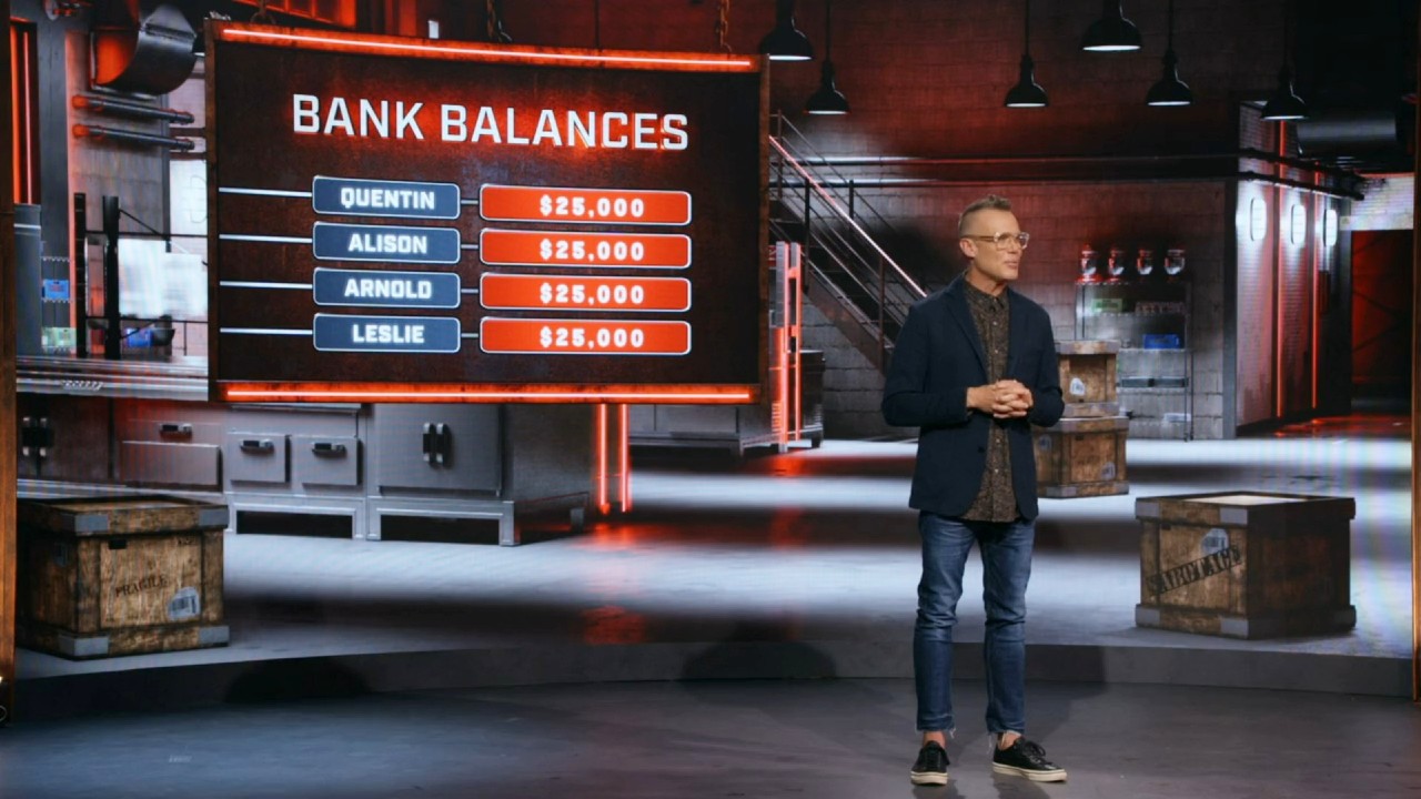 Brian Malarkey standing in front of a bank balances board in Cutthroat Kitchen: Knives Out.