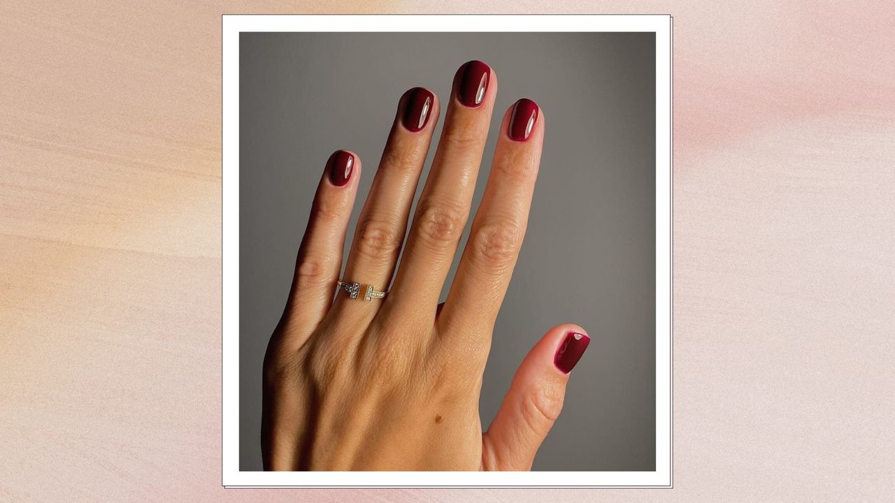 Hand with dark red short square nails, on a pink watercolour background