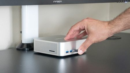A person plugging a 2.4 GHz USB dongle into one of the front ports on the Geekom A9 Max 2026 Edition