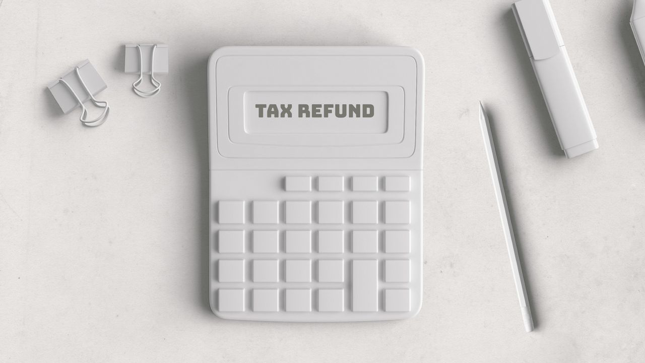 White calculator that reads &quot;Tax Refund&quot; next to a white pencil and some paper clips