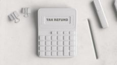 White calculator that reads "Tax Refund" next to a white pencil and some paper clips