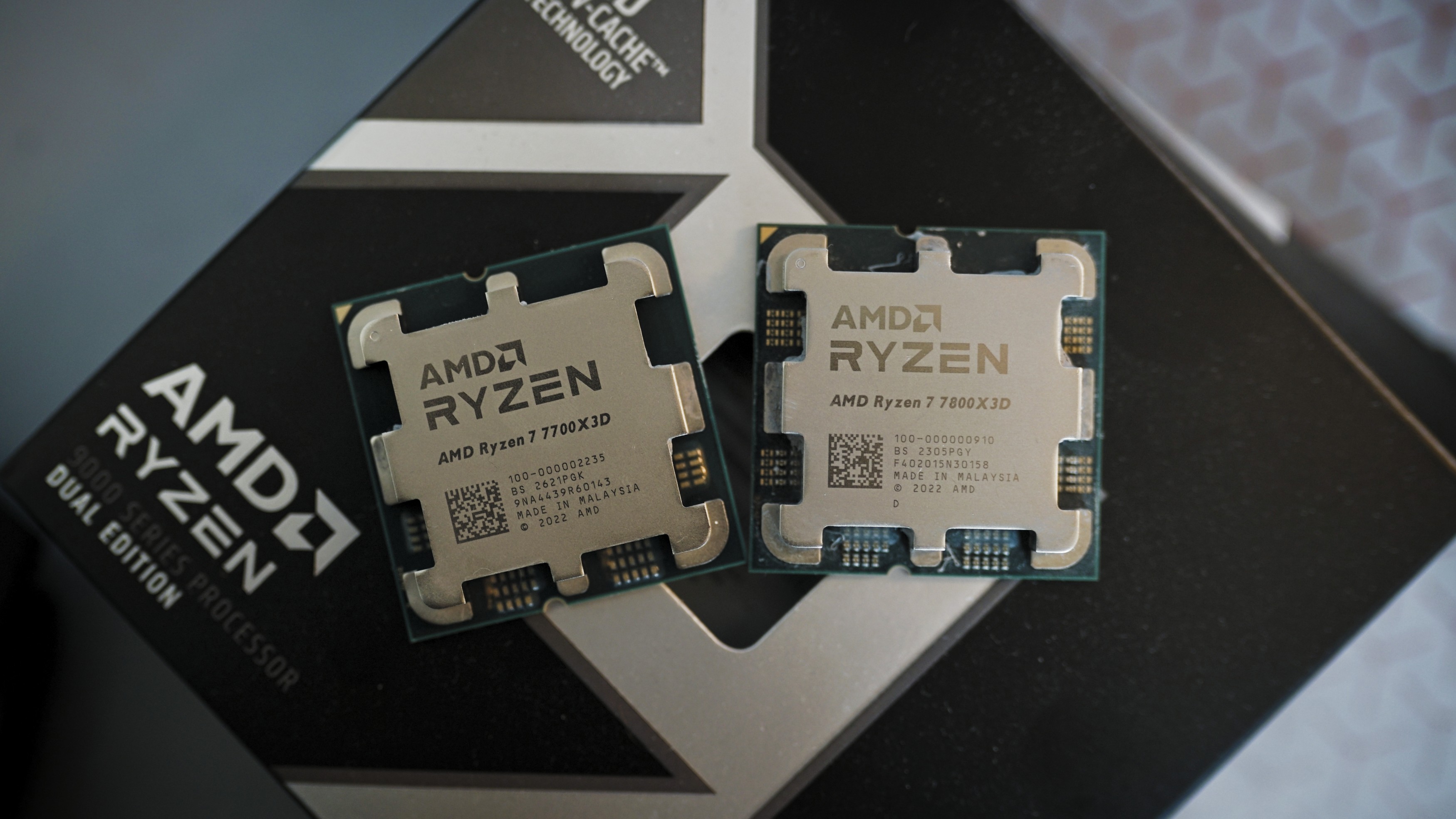 Ryzen 7 7800X3D and 7700X3D sitting next to each other.