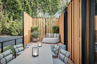 A secluded garden space with wood panelling at Il Sereno Hotel. Furniture includes a lounge chair, table and dining chairs