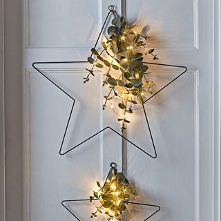Two metal star frames with lights and eucalyptus