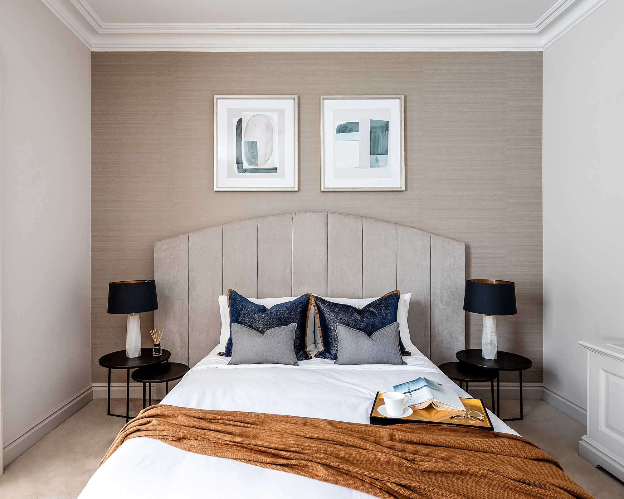 A grey bedroom idea with warm brown-grey walls, taupe headboard and an ochre throw on the bed