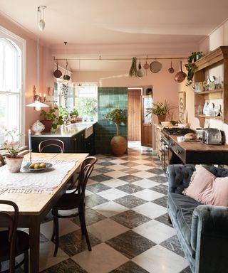 Blush kitchen with checkered floor tiles in black and white, dining table, sofa